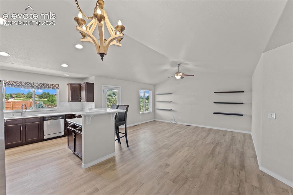 Image 7 of 40: Open-concept living space featuring wood-finish flooring throughout, vaulte