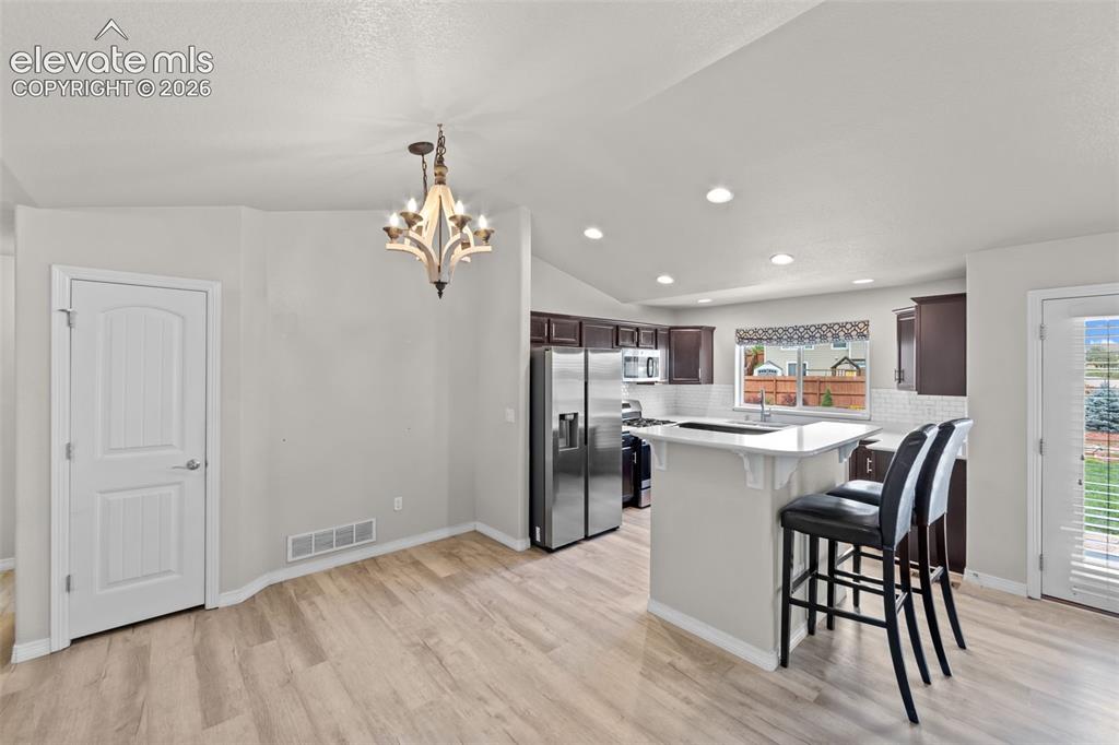 Image 8 of 40: Open-concept kitchen and dining area featuring stainless steel appliances,