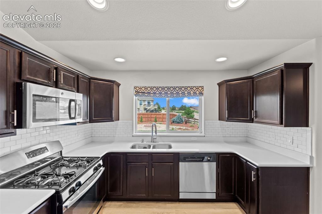 Image 9 of 40: U-shaped kitchen with dark wood cabinetry, stainless steel appliances, whit