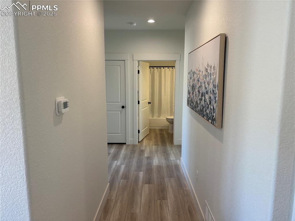 Image 11 of 19: Hallway featuring light wood-type flooring, a textured wall, and recessed l