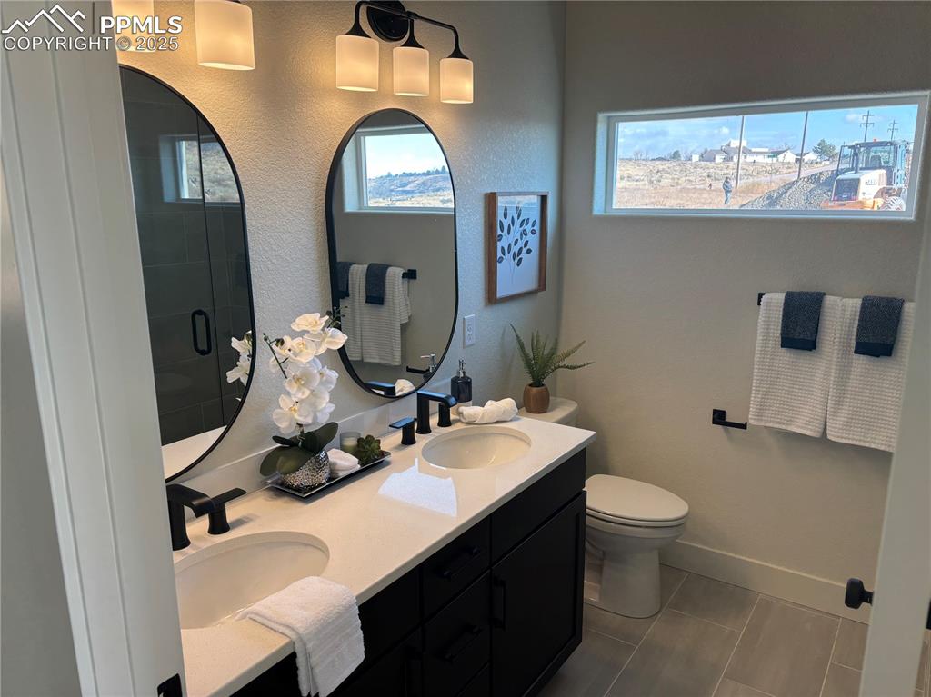 Image 17 of 19: Bathroom with double vanity, dark tile patterned flooring, and a shower sta