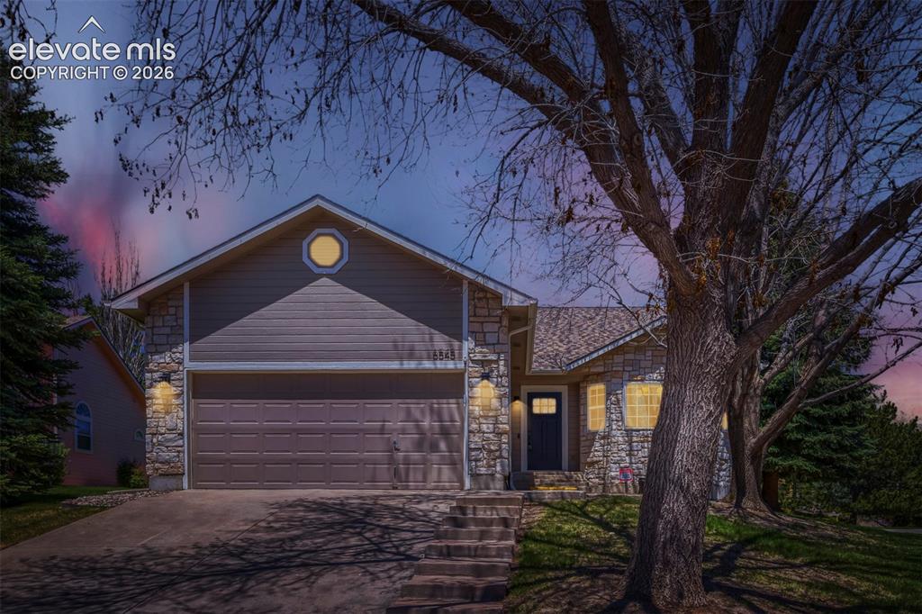Caption: Ranch home featuring a stone and horizontal siding exterior, an attached two-car garage with a panel