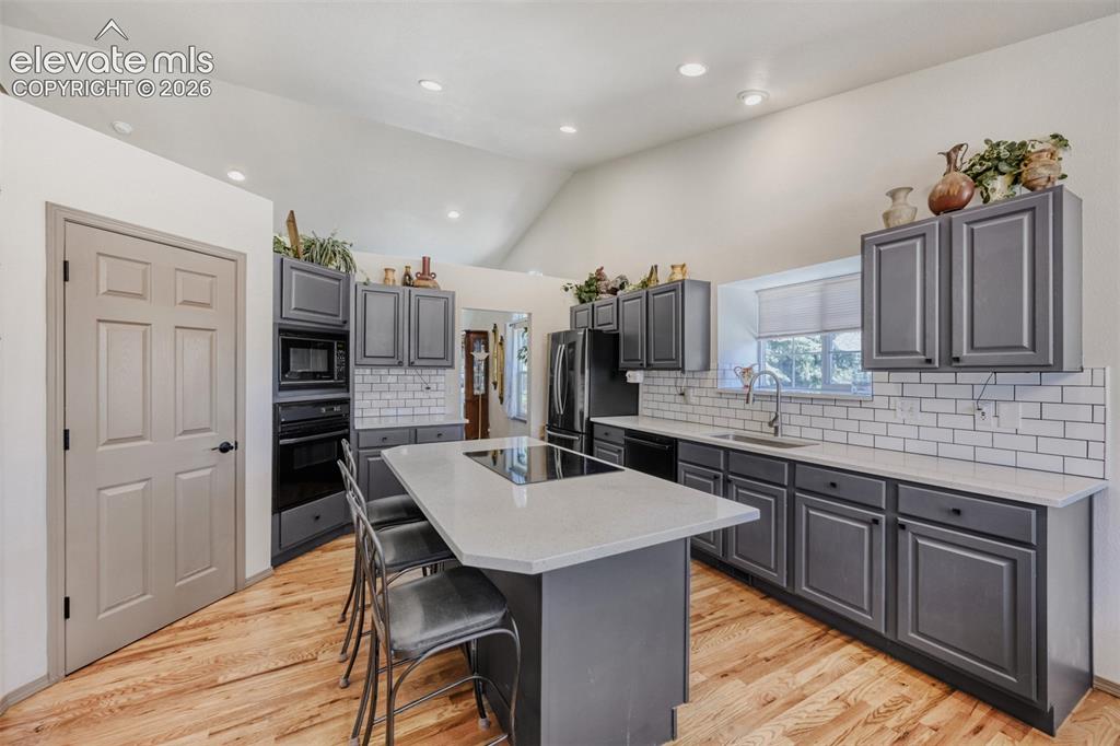 Image 10 of 29: Modern kitchen featuring a central island with 
integrated cooktop, light 