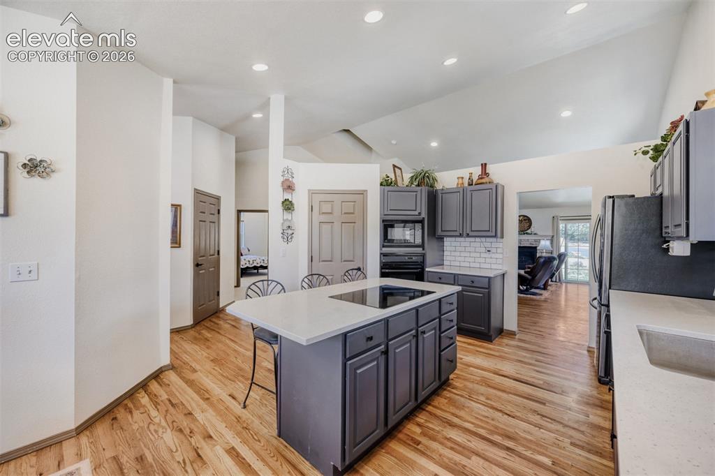 Image 11 of 29: Bright kitchen featuring a central island with an integrated cooktop, grey 