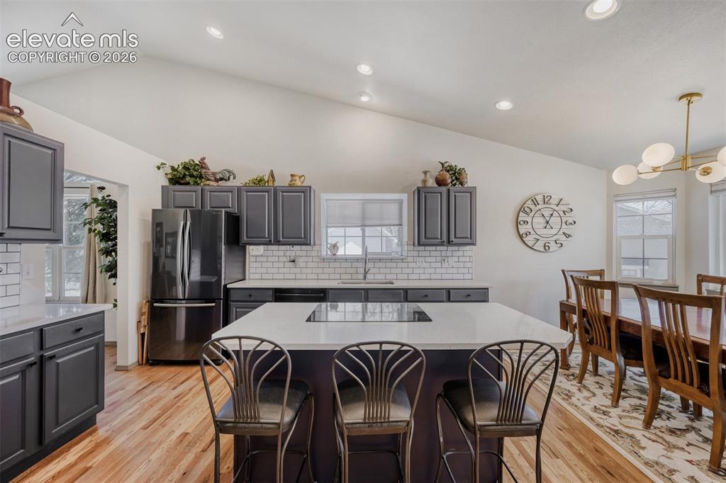 Image 12 of 29: Kitchen featuring dark-toned cabinetry, light countertops, subway tile back