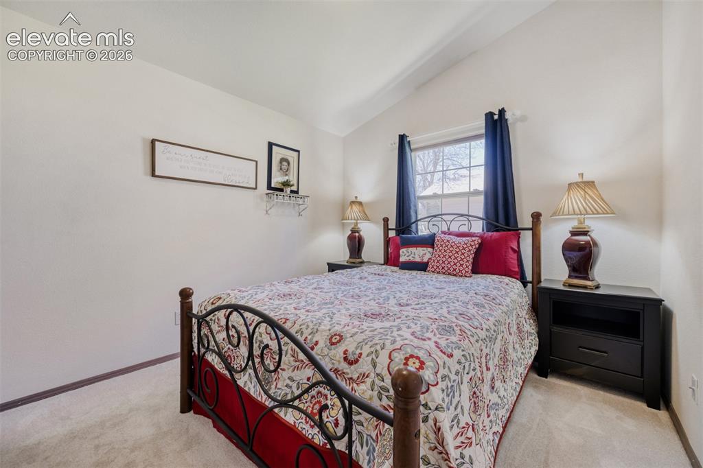 Image 20 of 29: Vaulted ceiling bedroom featuring a window with natural light, neutral wall