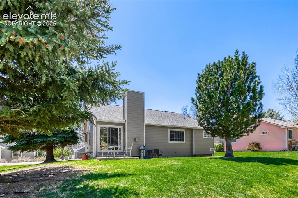 Image 27 of 29: Expansive rear yard featuring a verdant lawn and mature trees