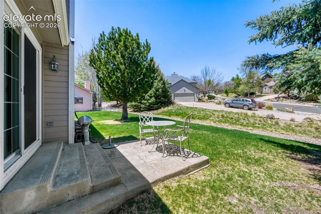 Image 29 of 29: Rear patio with concrete steps and an adjacent grassy area