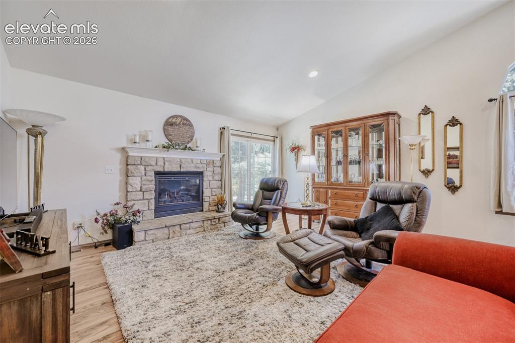 Image 5 of 29: Living area featuring a stone-clad fireplace with
 a raised hearth, a 
va