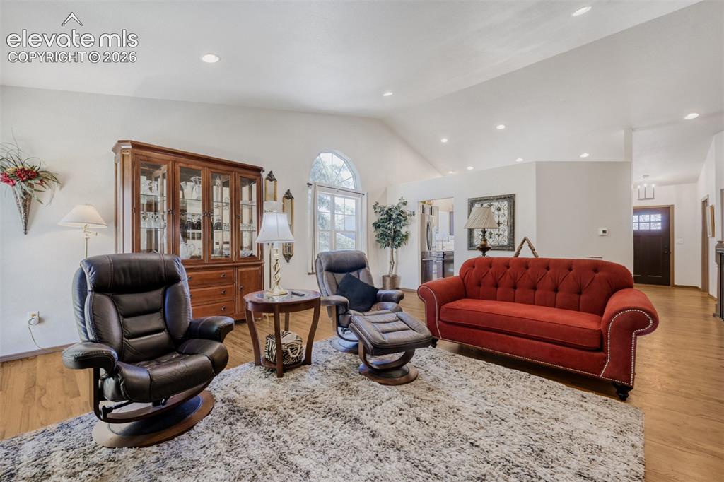 Image 6 of 29: Spacious living area featuring wood-finish 
flooring, vaulted ceilings, an
