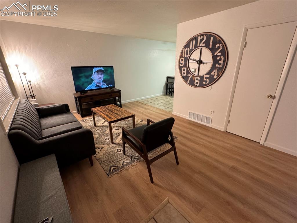 Image 16 of 28: 211-Unit C Living room with light LVP flooring looking toward tiled kitchen