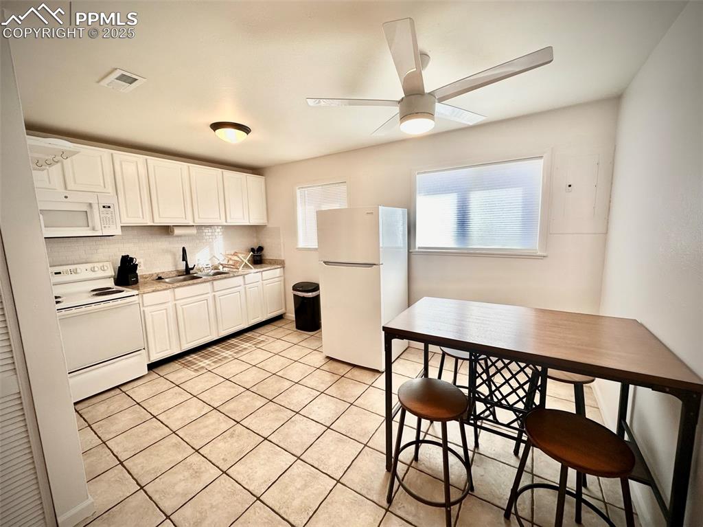 Image 27 of 28: 211-Unit D  Kitchen with white appliances, white cabinets, light countertop