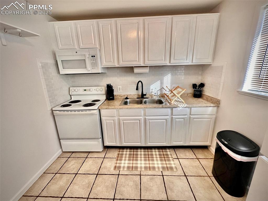 Image 28 of 28: 211-Unit D  Kitchen featuring white appliances, white cabinetry, light coun