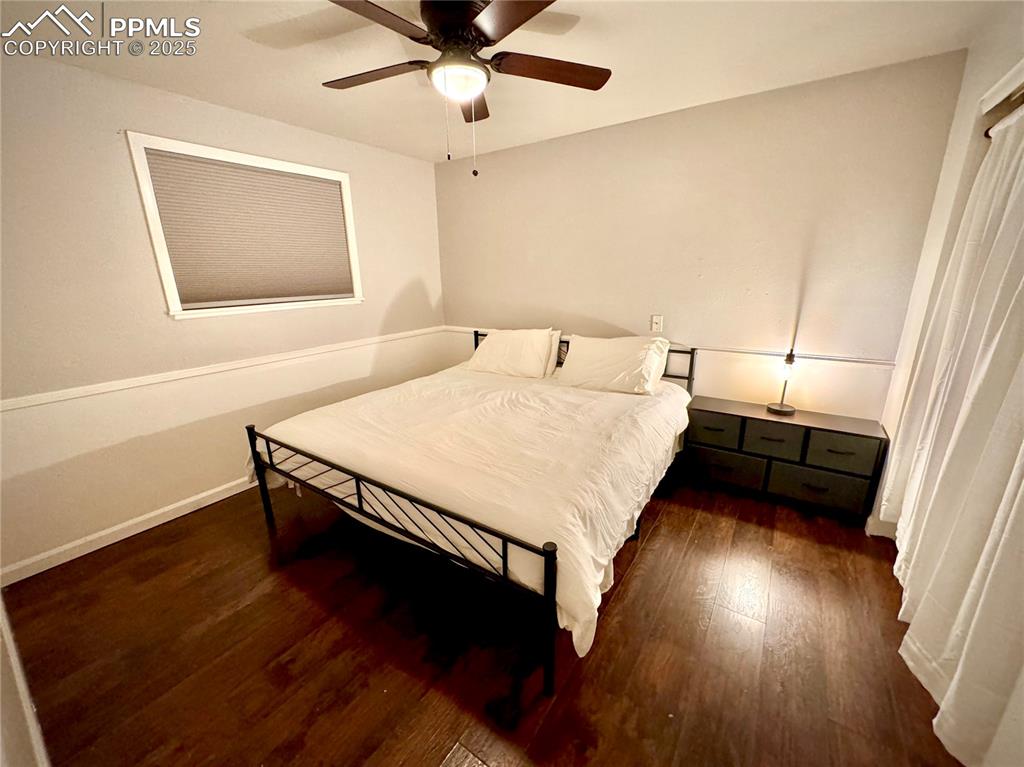 Image 6 of 28: 211-Unit A Bedroom 1 featuring dark wood-type flooring and ceiling fan