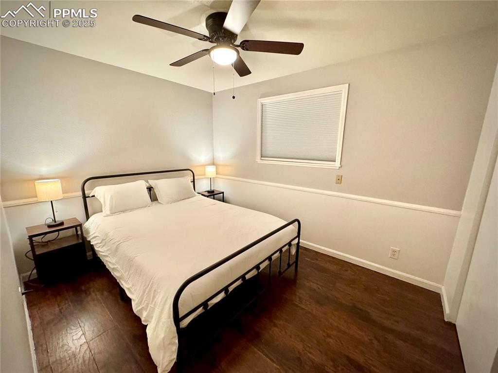 Image 7 of 28: 211-Unit A Bedroom 2 featuring dark LVP floors and ceiling fan
