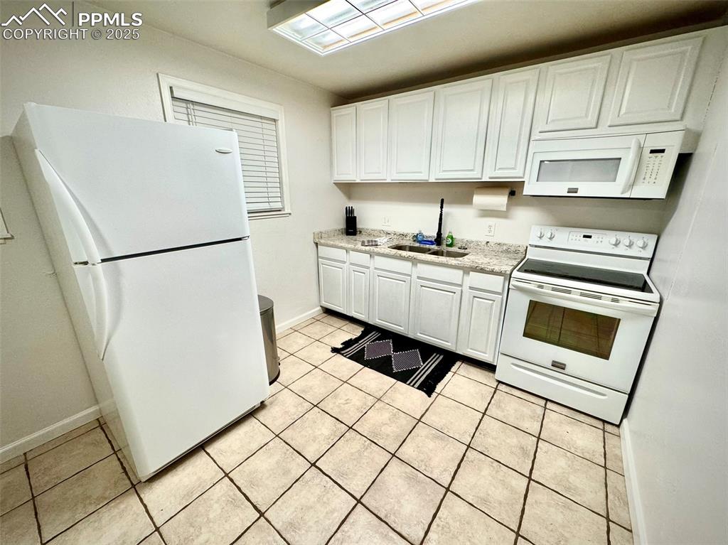 Image 9 of 28: 211-Unit A Kitchen with white appliances, white cabinetry, and light tile p