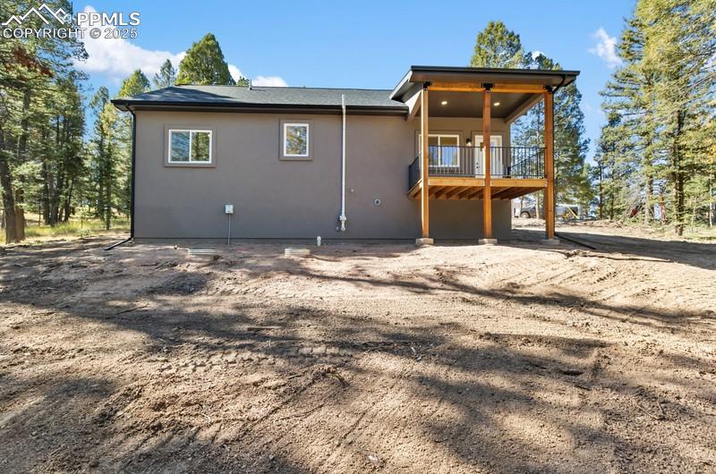 Image 10 of 37: Rear view of property featuring a wooden deck and stucco siding