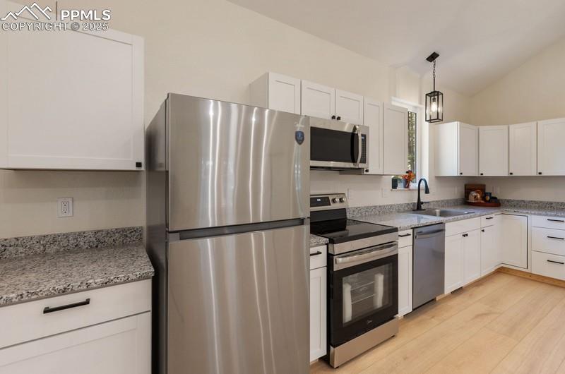 Image 17 of 37: Kitchen with appliances with stainless steel finishes, white cabinets, ligh