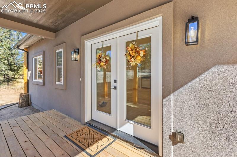 Image 2 of 37: Property entrance with stucco siding and a wooden deck