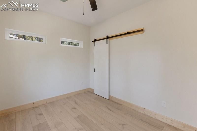 Image 28 of 37: Bedroom #3 with light wood-type flooring, a barn door to the closet and cei