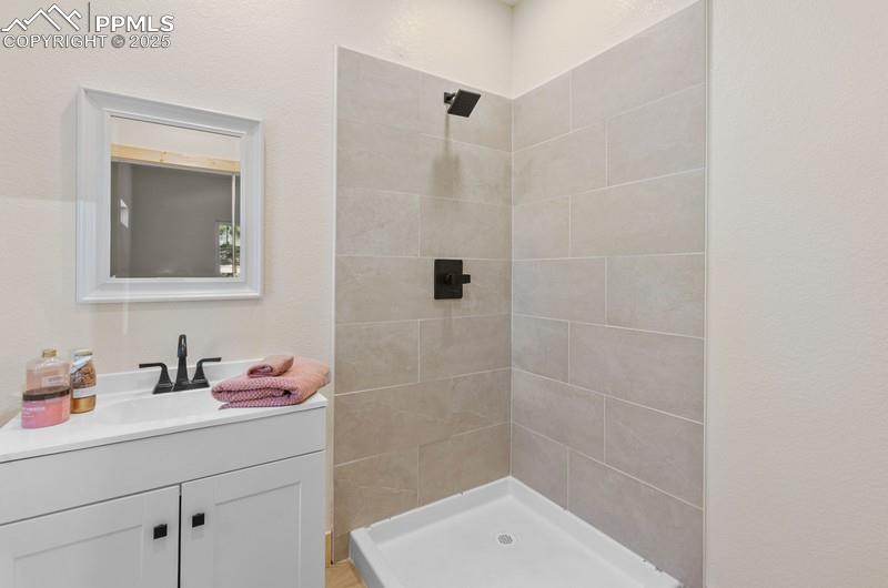 Image 30 of 37: Bathroom with a stall shower, vanity, and a textured wall