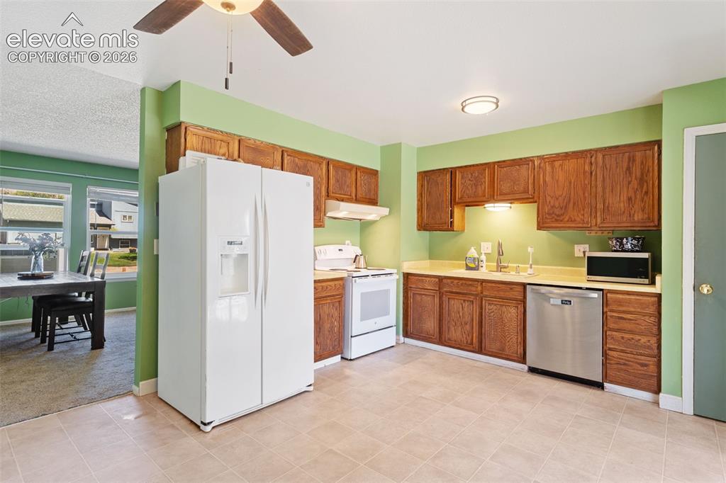 Image 10 of 36: Kitchen featuring wood cabinetry, light-toned countertops, and a full suite