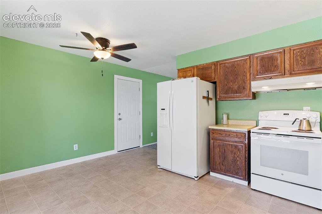 Image 11 of 36: Kitchen area featuring wood cabinetry, white appliances, and light-toned ti