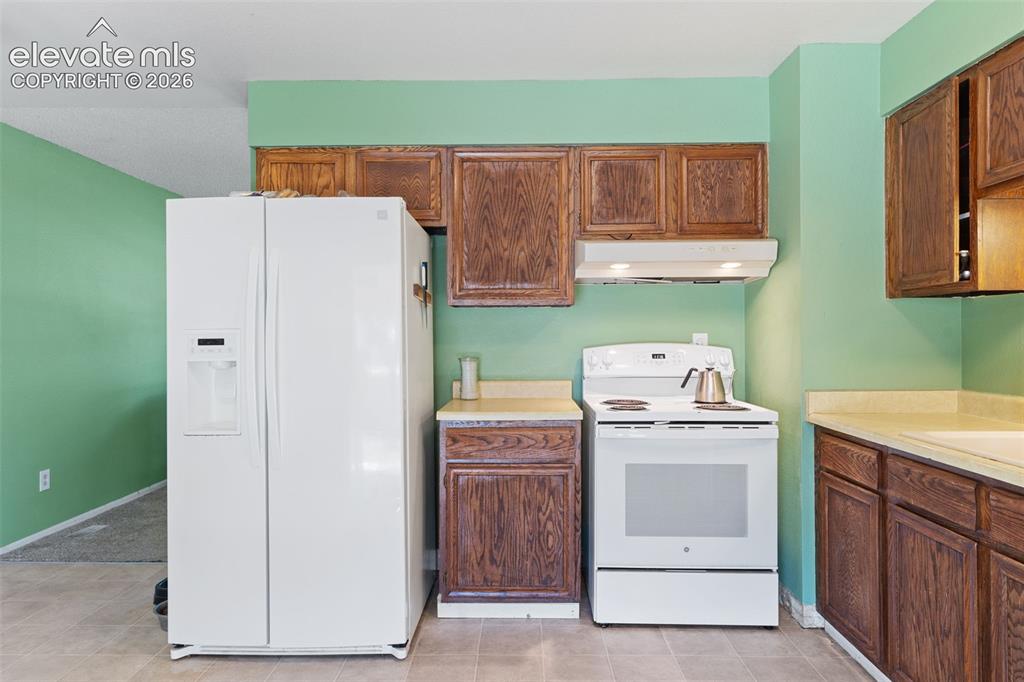 Image 13 of 36: Kitchen featuring wood cabinetry, light-toned countertops, and tile floorin