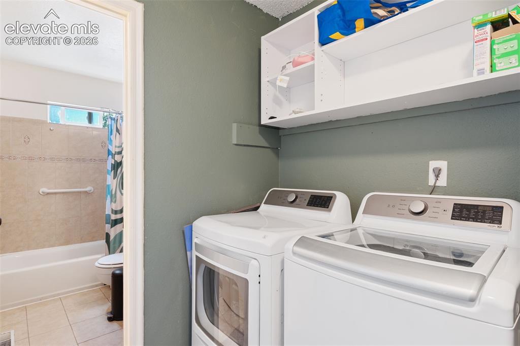 Image 22 of 36: Dedicated laundry area featuring a washer and dryer, complemented by overhe