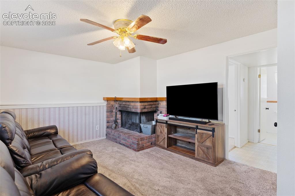Image 25 of 36: Spacious recreation room showcasing a wood-burning fireplace with brick sur