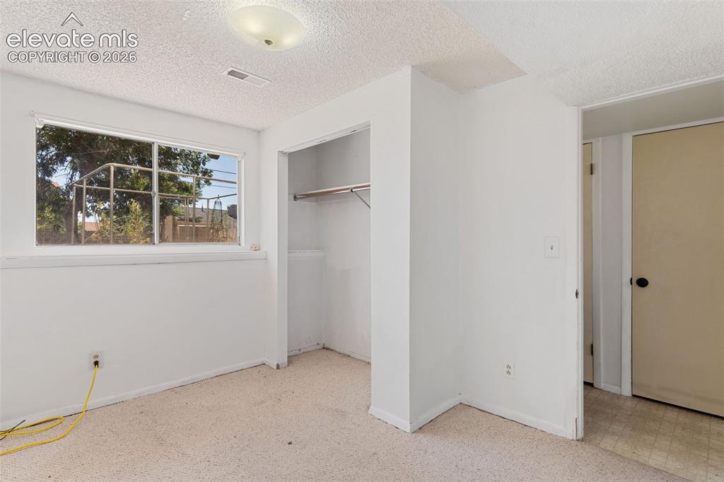 Image 28 of 36: Room with white painted walls, textured ceiling, and light-colored carpet f
