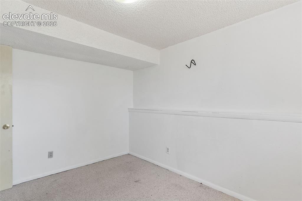 Image 30 of 36: Carpeted room with white walls, a textured ceiling, and a light-colored doo
