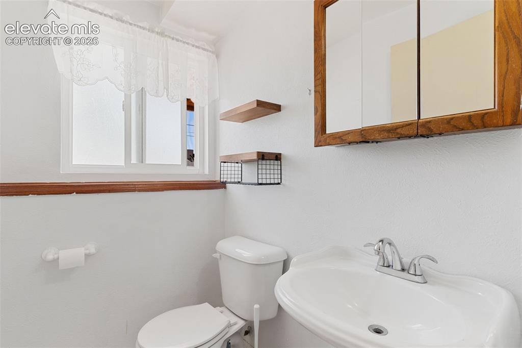 Image 32 of 36: Bathroom featuring a wall-mounted sink with a chrome faucet, a white toilet