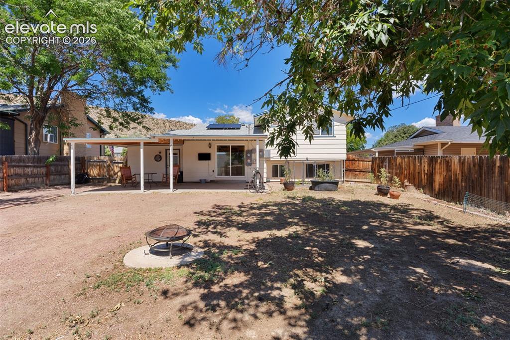 Image 35 of 36: Expansive backyard featuring a covered patio, multiple windows and sliding