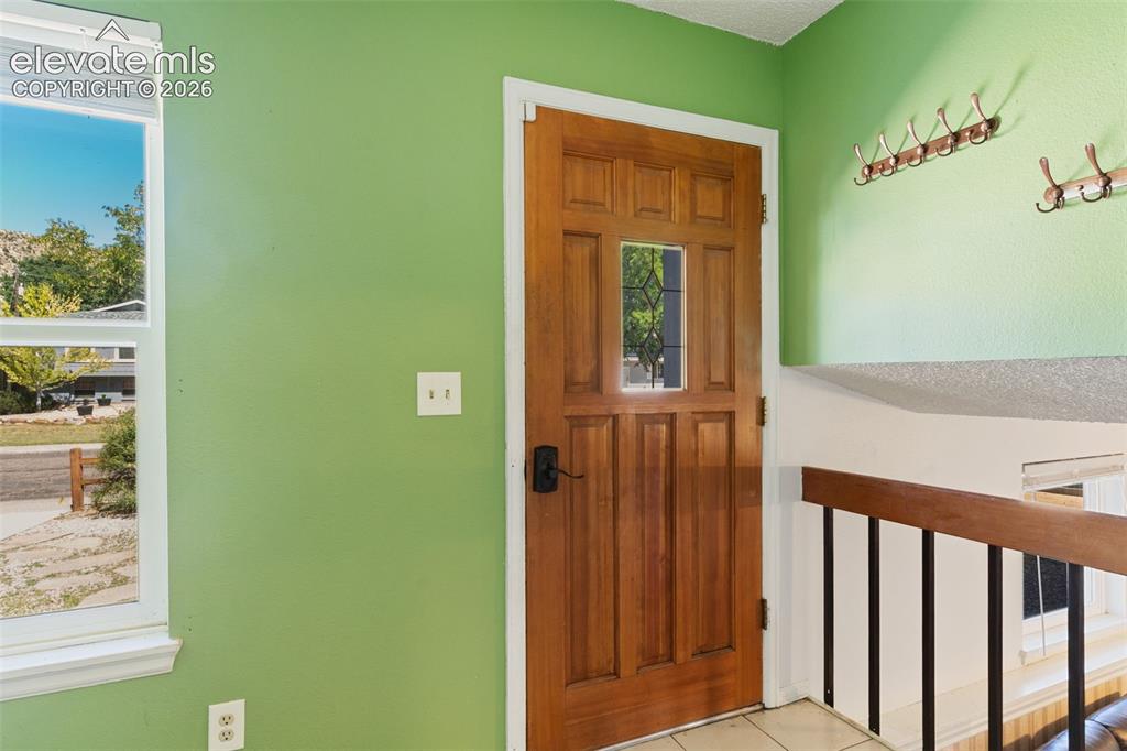 Image 4 of 36: Bright entryway showcasing vibrant sage green walls, a six-panel wood door
