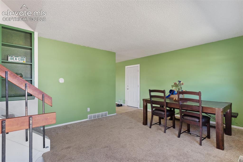 Image 5 of 36: Carpeted room featuring light green walls, a built-in shelving unit, and a