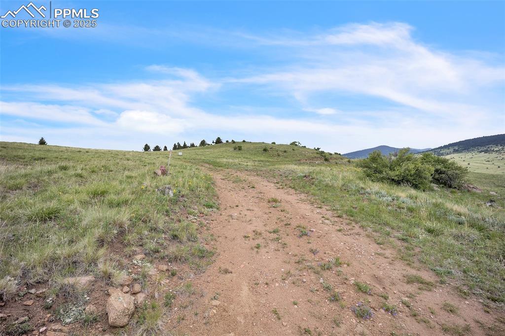 Image 3 of 9: View of dirt / gravel road featuring a view of countryside and a mountain v
