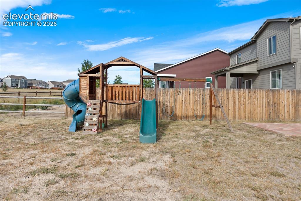 Image 22 of 26: Playset in large back yard