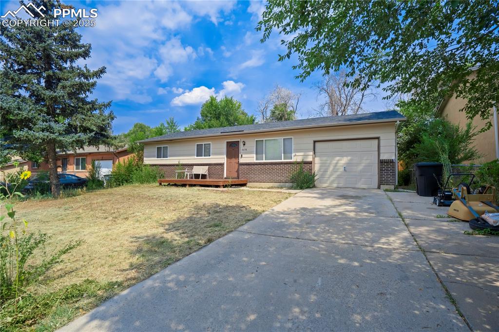 Caption: Single story home with brick siding, driveway, a garage, and a deck