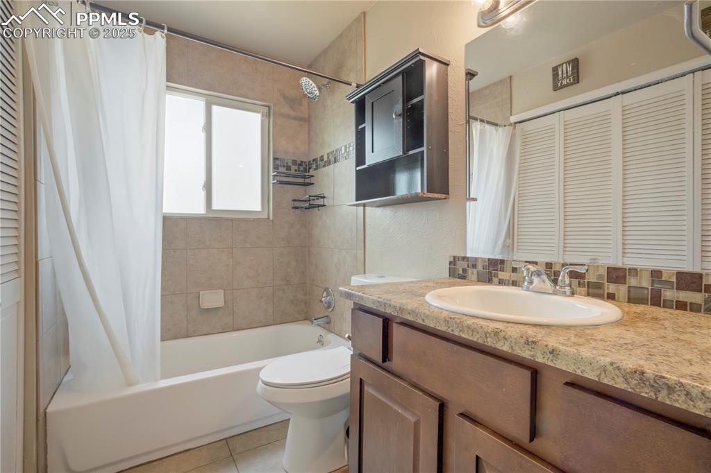 Image 11 of 22: Full bathroom with a closet, vanity, shower / tub combo, decorative backspl