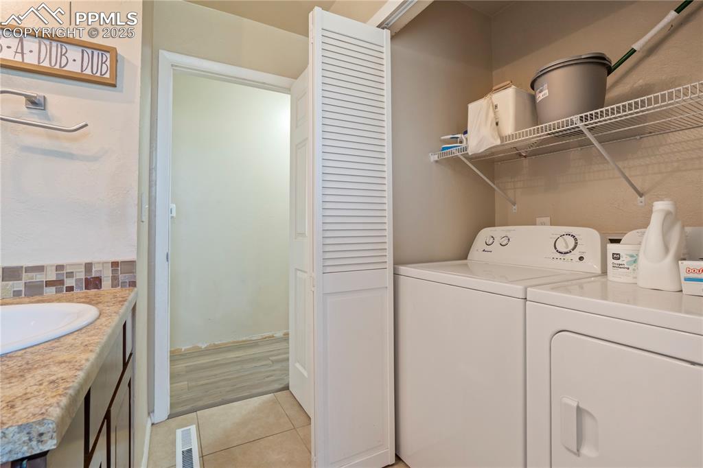 Image 12 of 22: Laundry room with light tile patterned floors and washing machine and cloth