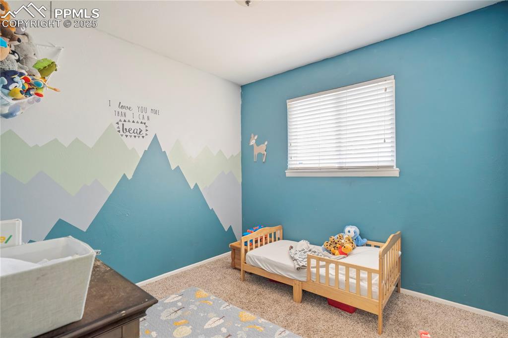 Image 13 of 22: Carpeted bedroom featuring a nursery area and an accent wall