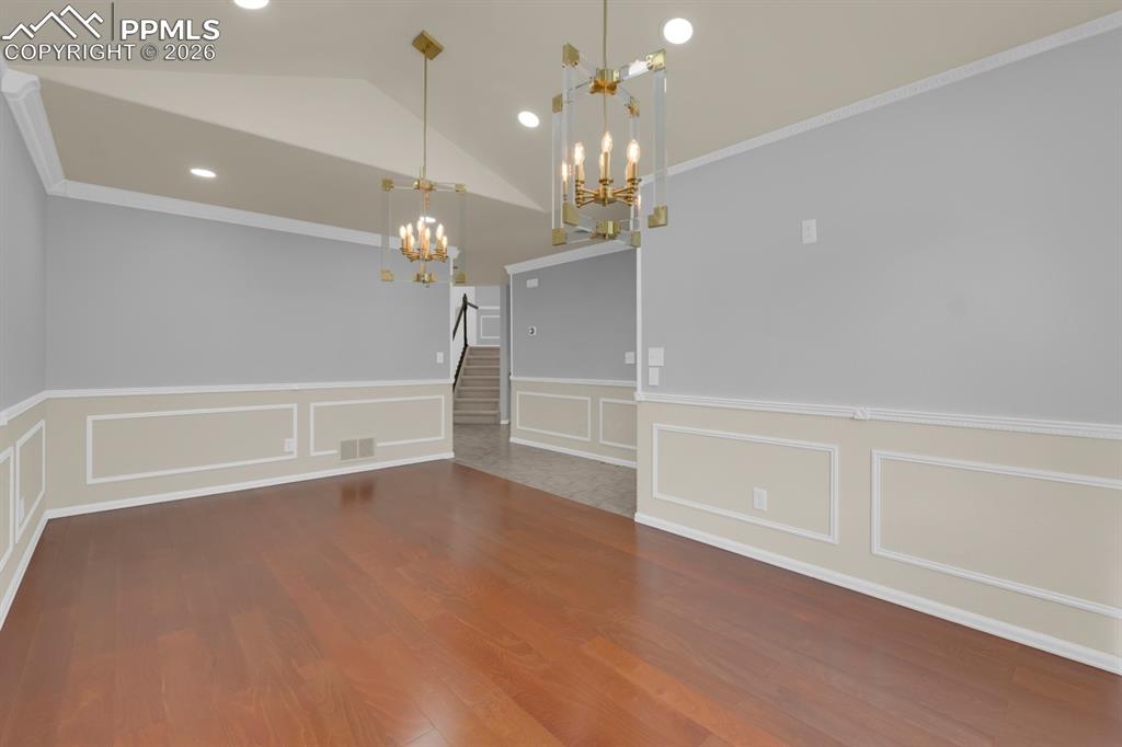Image 5 of 43: Formal dining area featuring crown molding, a chandelier, wood finished flo