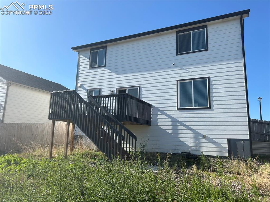 Image 5 of 10: Rear view of property featuring stairway and a wooden deck