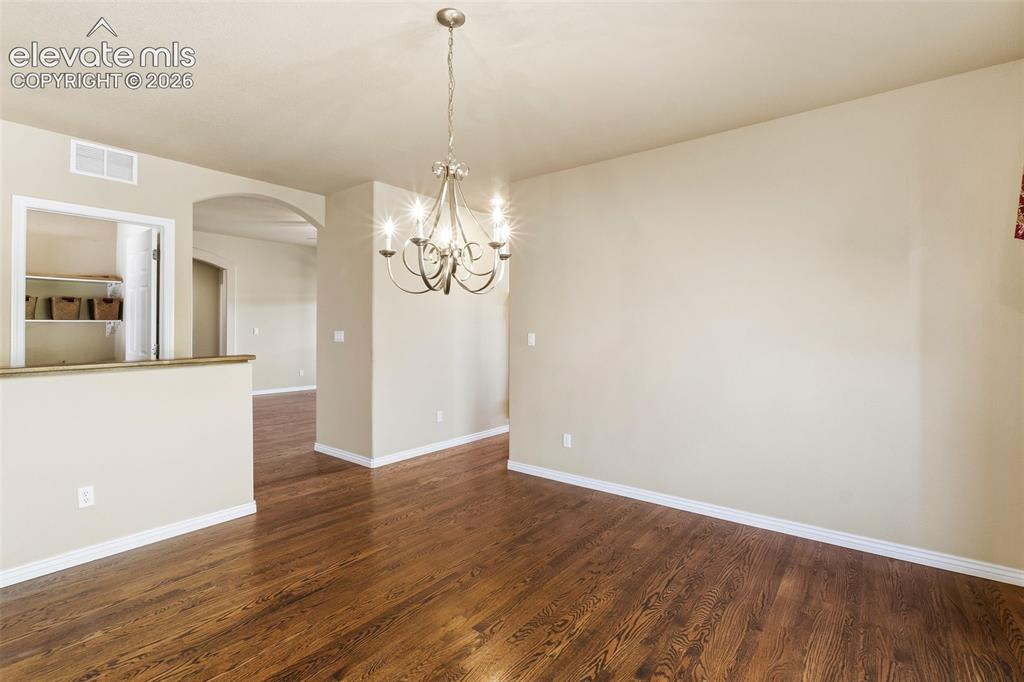Image 15 of 50: Wood-finish flooring, multi-arm metal chandelier, arched entryway, and buil