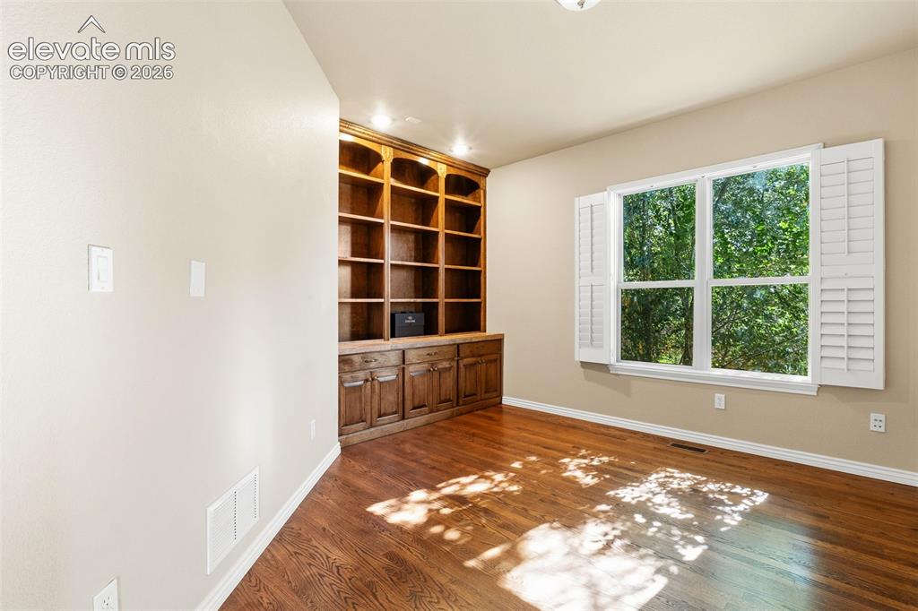 Image 25 of 50: OFFICE WITH BUILT-IN SHELVES AND PLANTATION SHUTTERS