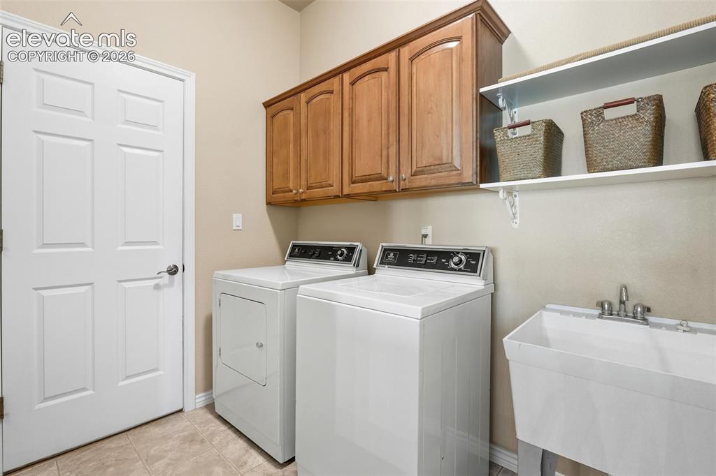 Image 29 of 50: Laundry space featuring wood-finish upper cabinetry, built-in open shelving