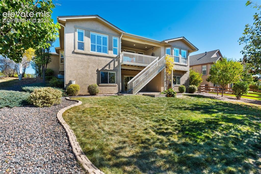 Image 39 of 50: Two-story stucco residence featuring an elevated wood deck with stairs, mul