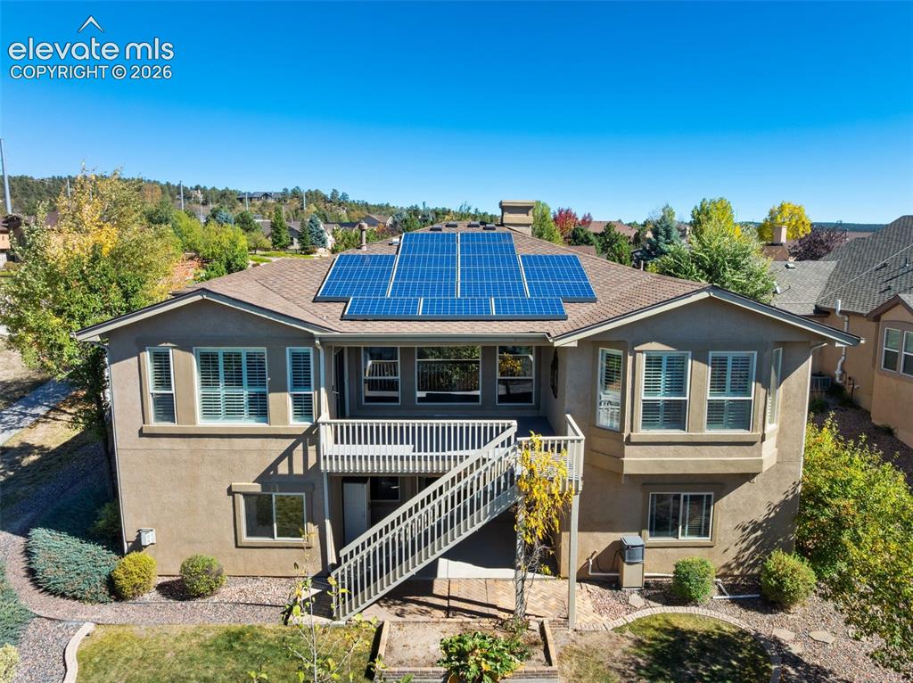 Image 41 of 50: Stucco exterior featuring an elevated deck with a staircase, rooftop solar