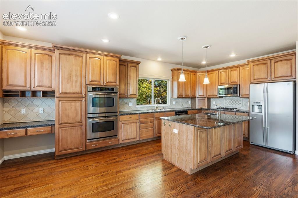 Image 7 of 50: Kitchen featuring wood cabinetry, stone countertops, stainless steel double